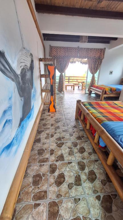 Cette chambre comprend deux lits et un tableau mural. dans l'établissement Casa Gaia Paradise, à Mompiche