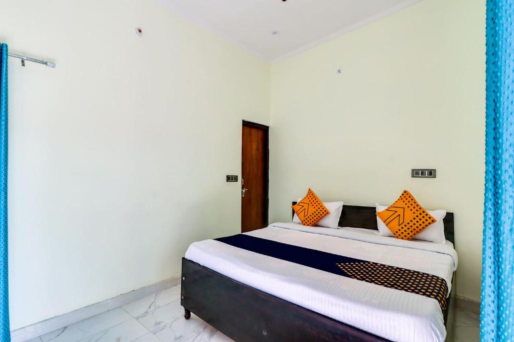 a bedroom with a bed with orange pillows on it at OYO 78256 Hotal Kesariya in Rewāri