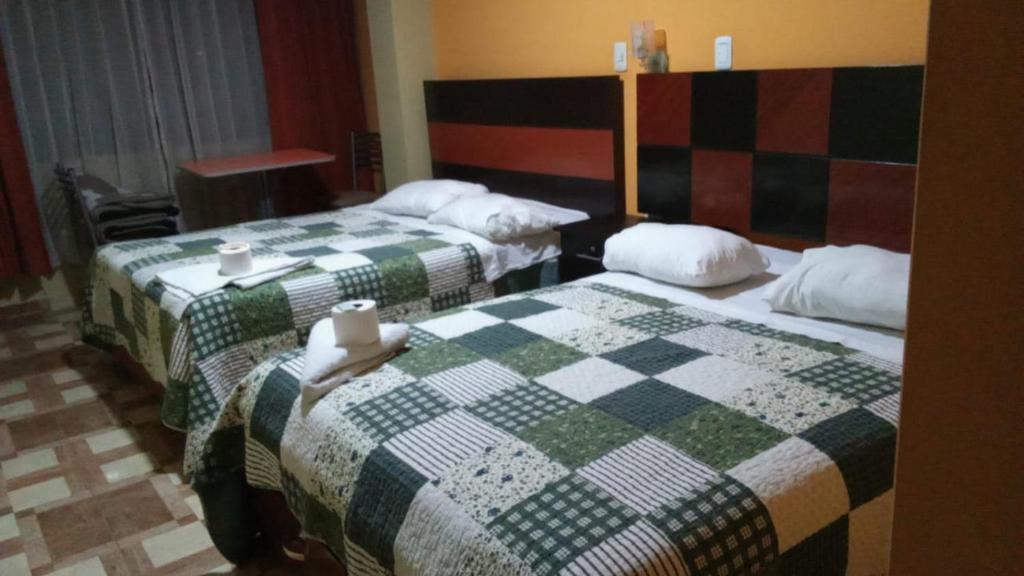 2 camas en una habitación de hotel con una manta a cuadros en HOTEL MAJHAMI, en Huancayo