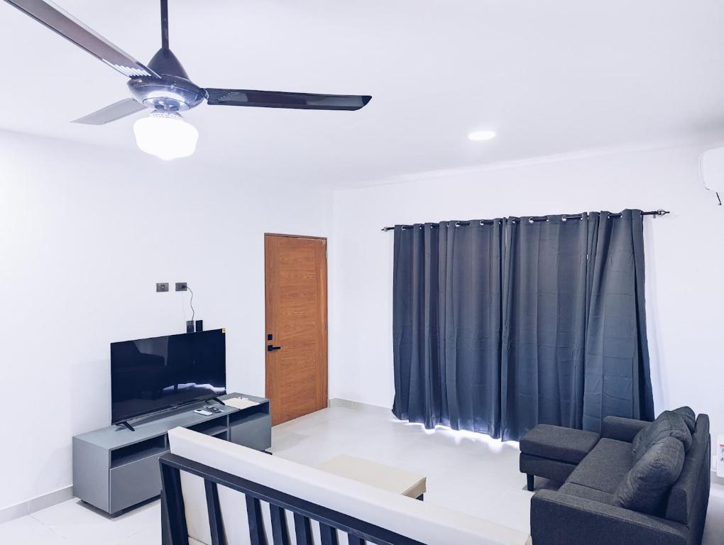 ein Wohnzimmer mit einem Deckenventilator und einem TV in der Unterkunft Apartment in Sosua - 4 Minutes From The Airport in San Felipe de Puerto Plata