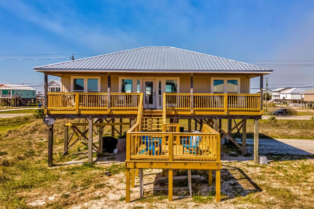 a house with a large deck with chairs in front of it at Just Chillin' in Dauphin Island