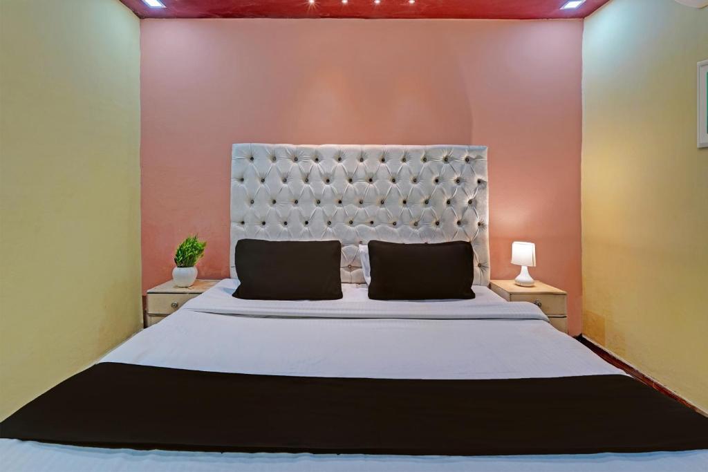 OYO Home Picturesque Stay في دهرادون: غرفة نوم بسرير ابيض كبير مع وسادتين