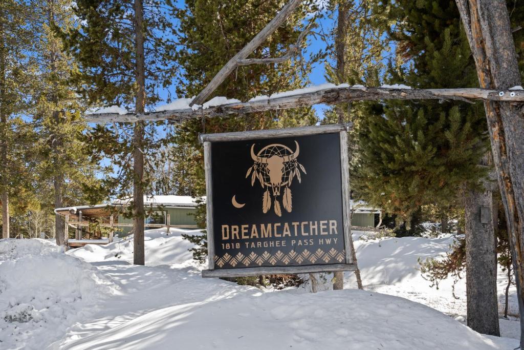a sign in the snow next to some trees at Dreamcatcher in West Yellowstone