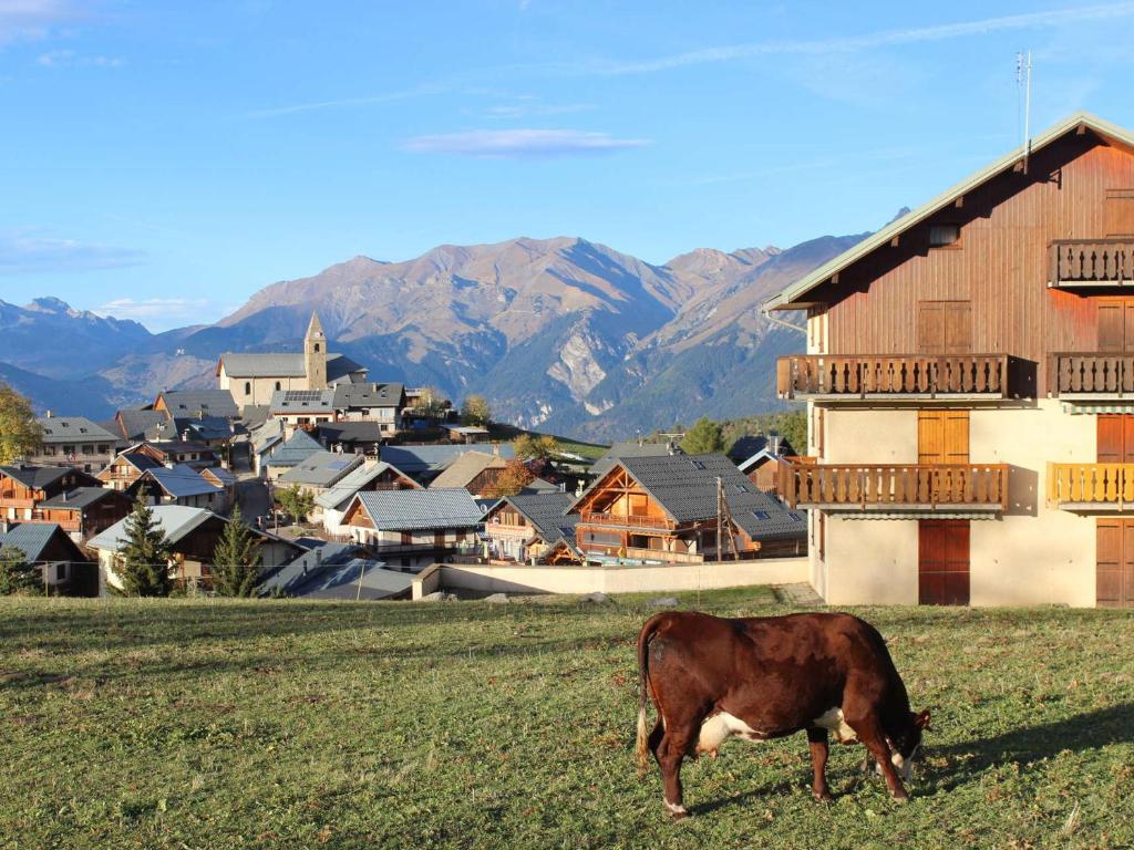 una vaca pastando en un campo frente a un pueblo en Studio Albiez-Montrond, 1 pièce, 4 personnes - FR-1-618-37, en Albiez-Montrond