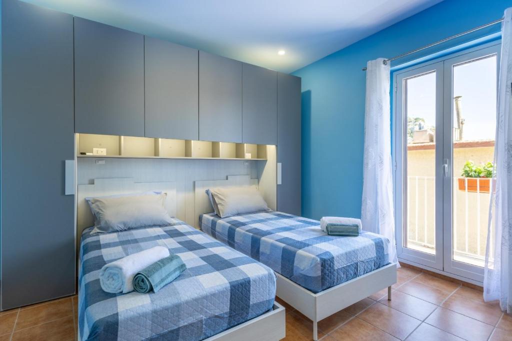 2 letti in una camera con pareti blu e finestra di Ibla nel Cuore a Ragusa