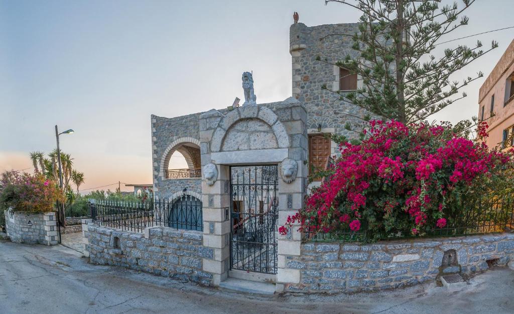 un edificio de piedra con una puerta y flores rosas en Casa Terra Mani, en Álika