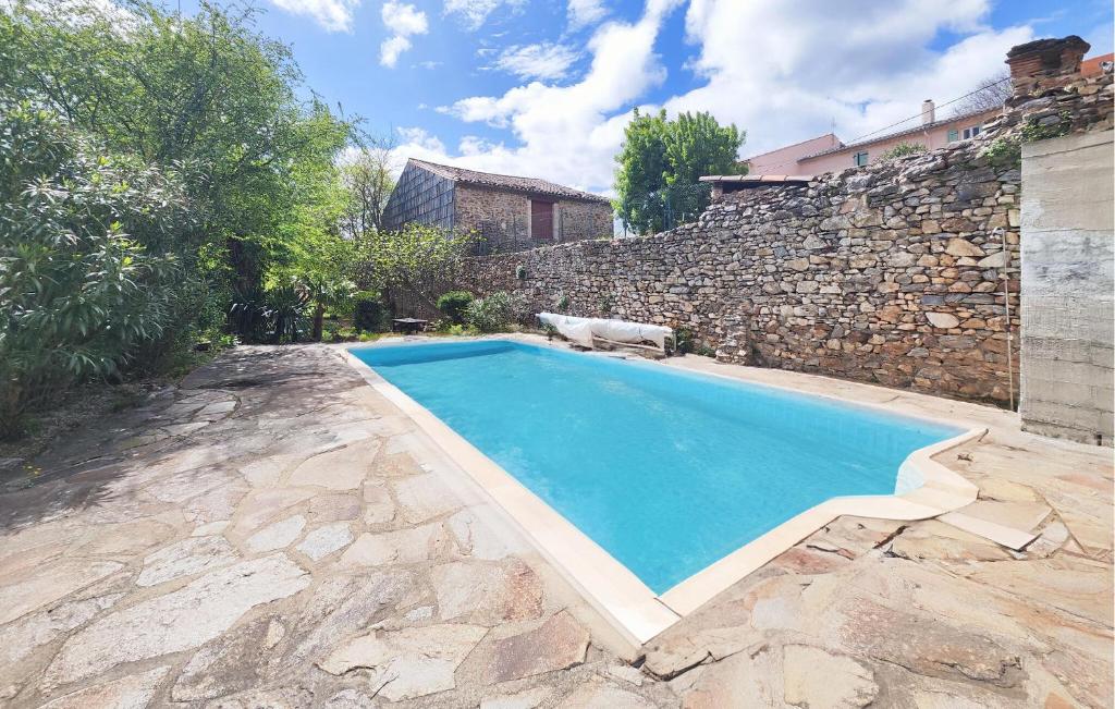 a swimming pool in front of a stone wall at Awesome Home In Faugres With Private Swimming Pool, Can Be Inside Or Outside in Faugères