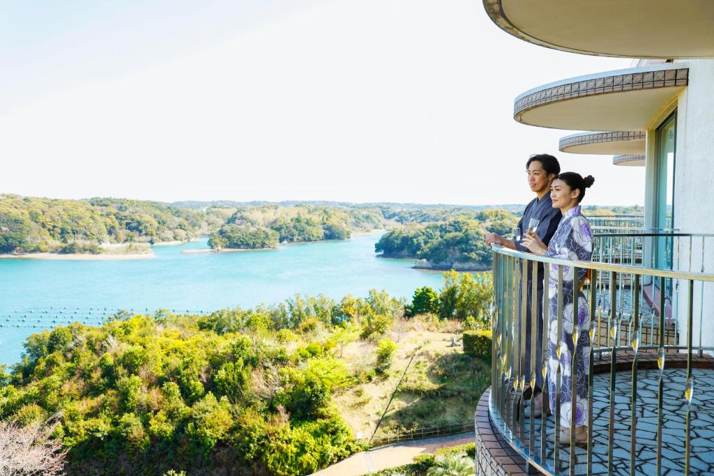 志摩的住宿－桑佩拉志摩酒店，男人和女人站在俯瞰河流的阳台