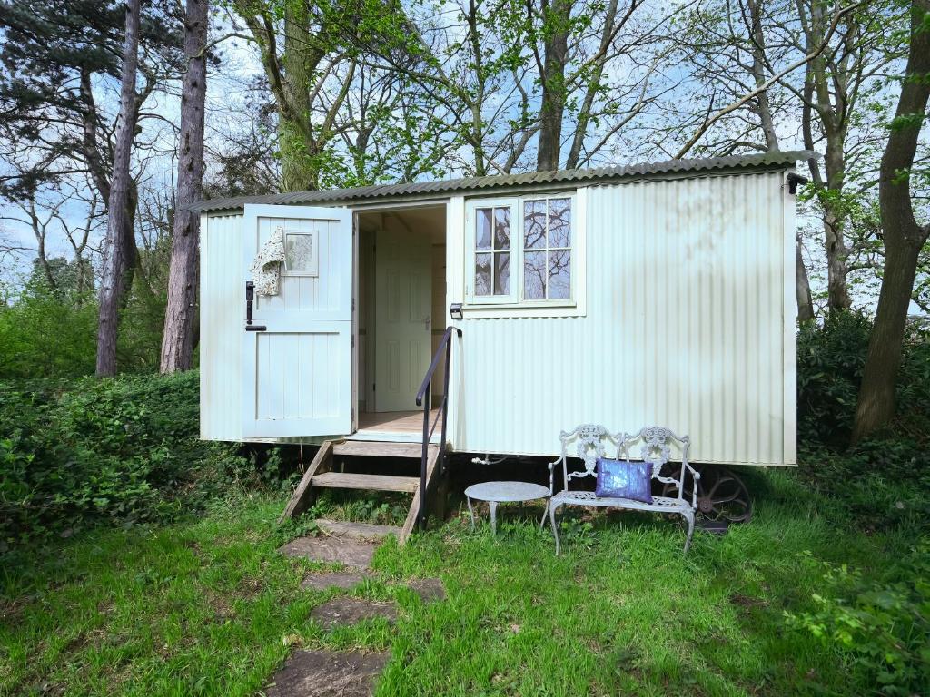 a small white shed with a bench and a chair at The Hideaway in Quatford