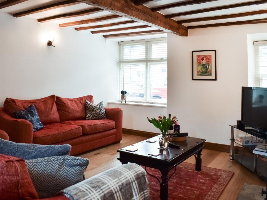 a living room with a red couch and a coffee table at Summerville Cottage in Kirkby Stephen