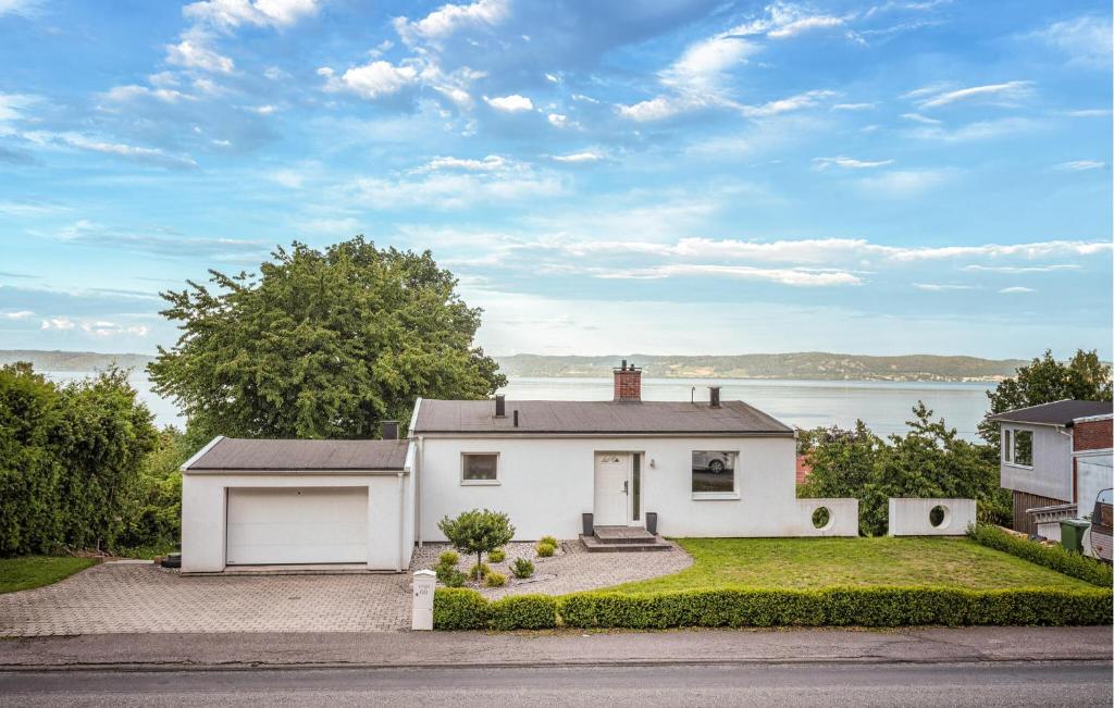 a white house with a garage and a body of water at 3 Bedroom Gorgeous Home In Bankeryd in Bankeryd