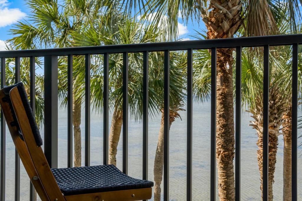 a chair on a balcony with palm trees and the beach at Sandestin Bayfront Studio with balcony and breathtaking views in Destin