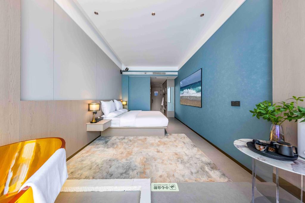 una camera con letto e parete blu di Kunming Yuxi Hotel a Kunming