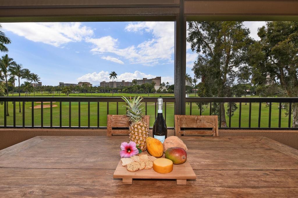 a table with a bunch of fruit and a bottle of wine at Kaanapali Royal C202 in Lahaina