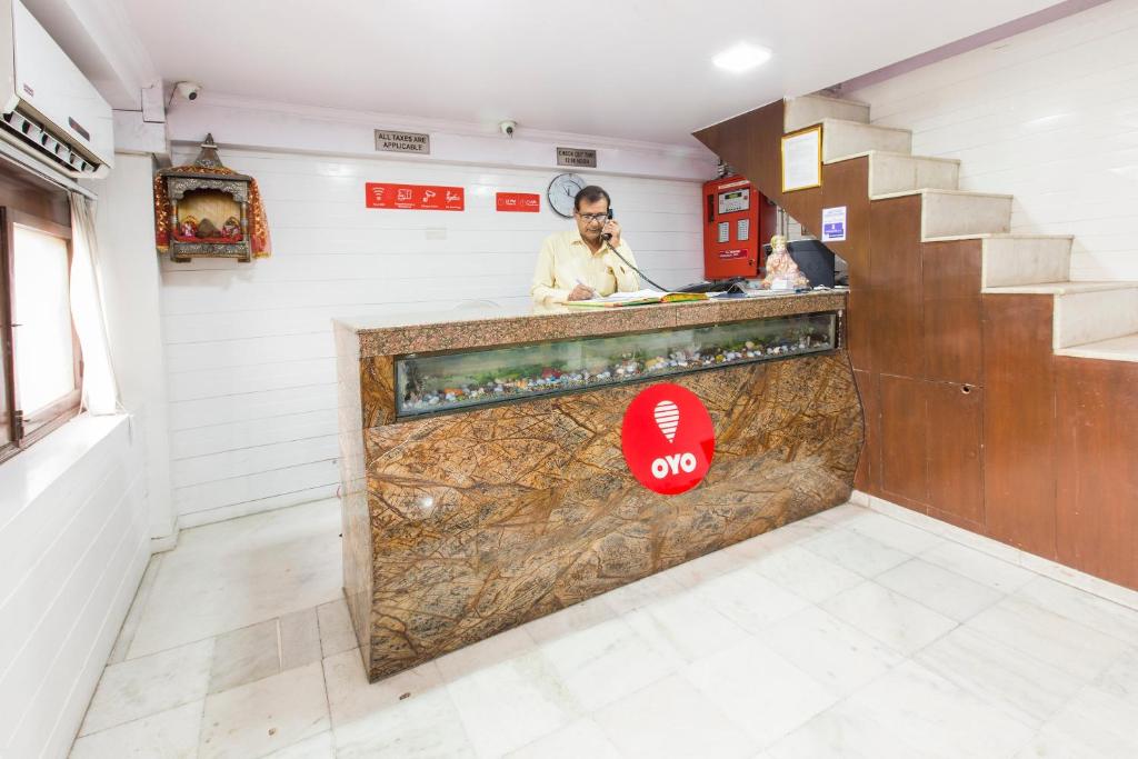 un hombre hablando por teléfono en un mostrador en una habitación en OYO Hotel Landmark Inn en Nueva Delhi