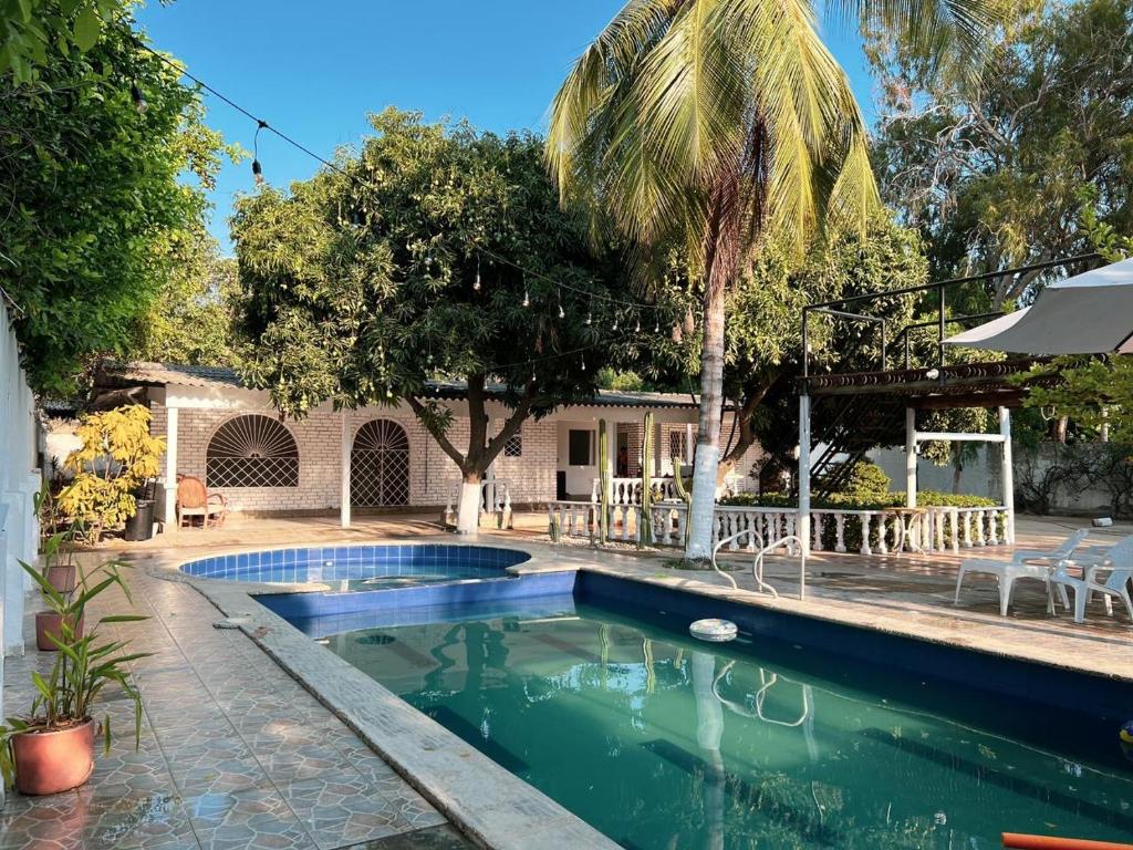 uma piscina num quintal com uma palmeira em Casa campestre con piscina cerca al aeropuerto y la playa em Santa Marta