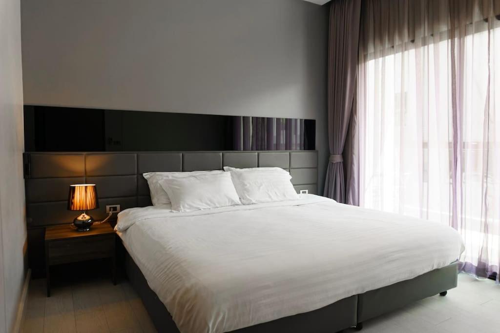 a bedroom with a large white bed and a window at Luxury Lake Condo next to Beach in Rawai Beach