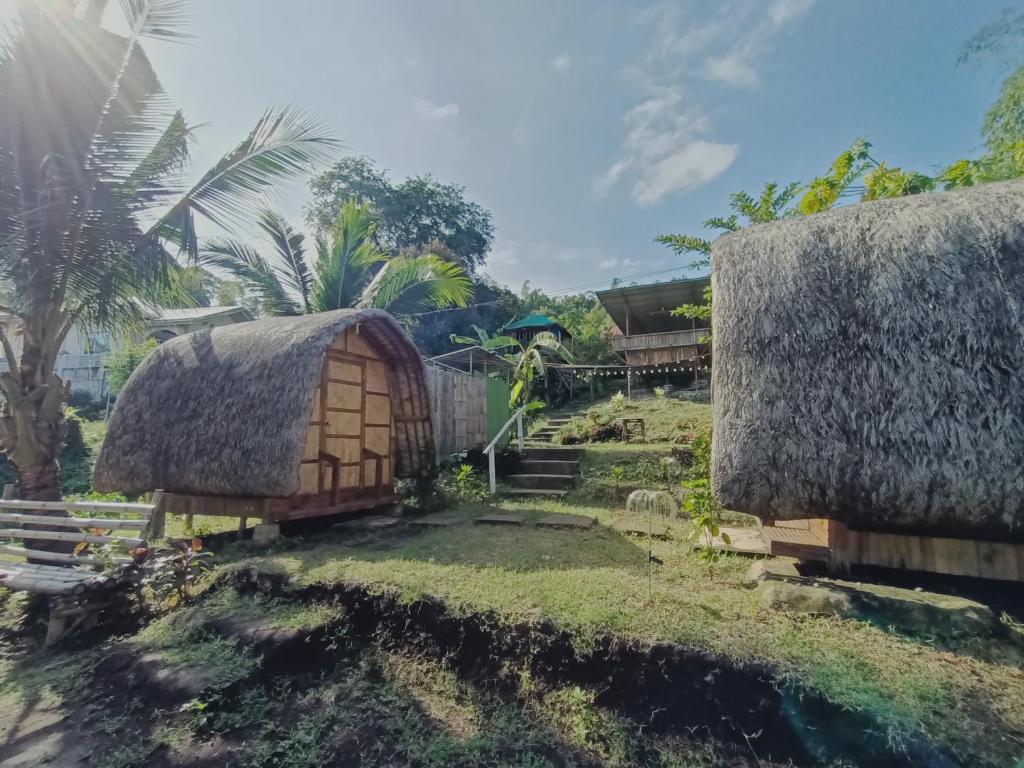 a group of buildings with grass roofs and trees at Bon Joy's Transient House in Mabini