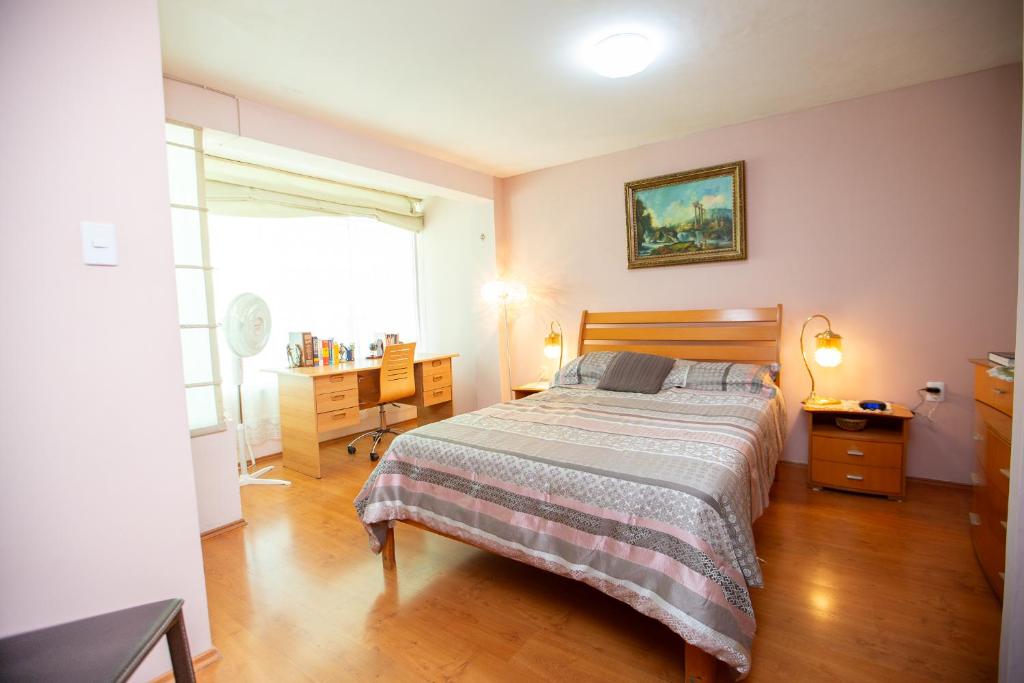 Habitación doble matrimonial con baño y jacuzzi compartido في Tlazcalancingo: غرفة نوم بسرير ومكتب ونافذة