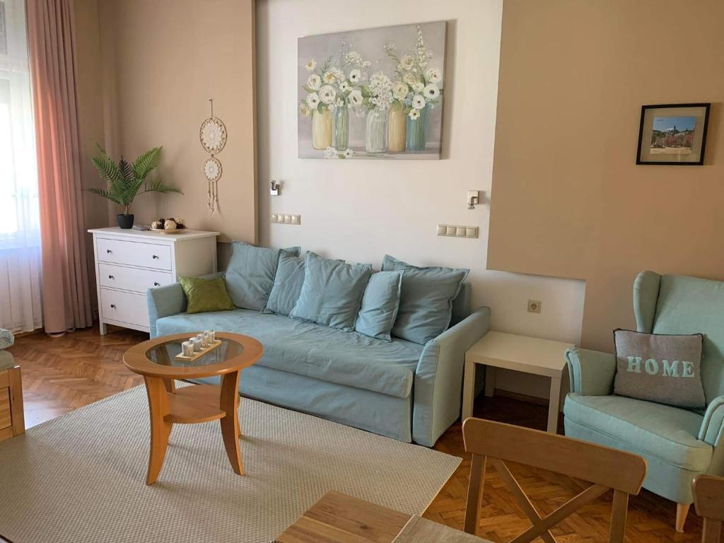 a living room with a blue couch and a table at Hangulat apartman in Miskolc