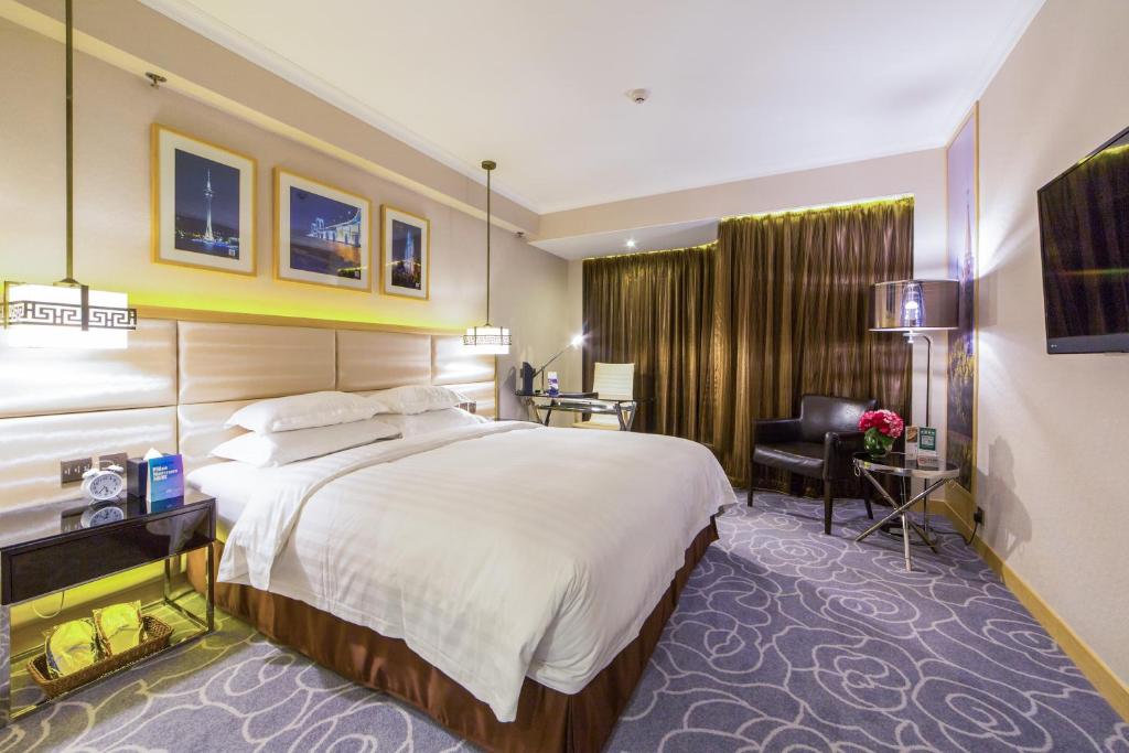マカオにあるメトロパーク ホテル マカオの大きなベッドとデスクが備わるホテルルームです。