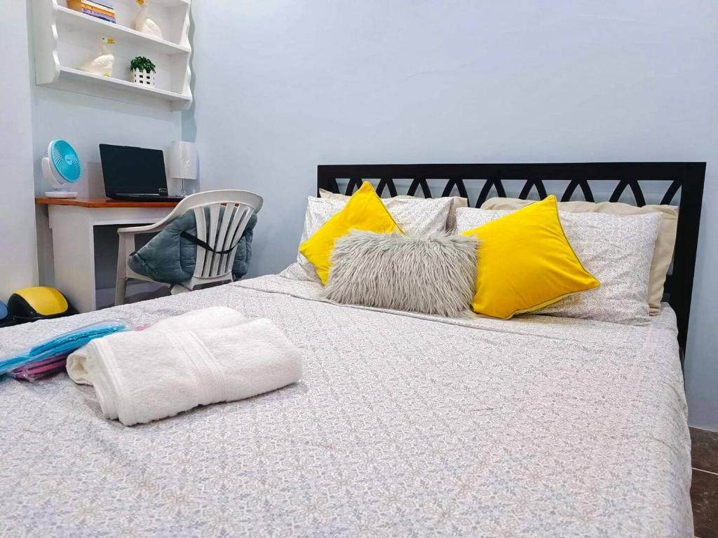 uma cama com almofadas amarelas e brancas em CamiStays Homestay in Camiguin, Best for Groups or Family em Mambajao