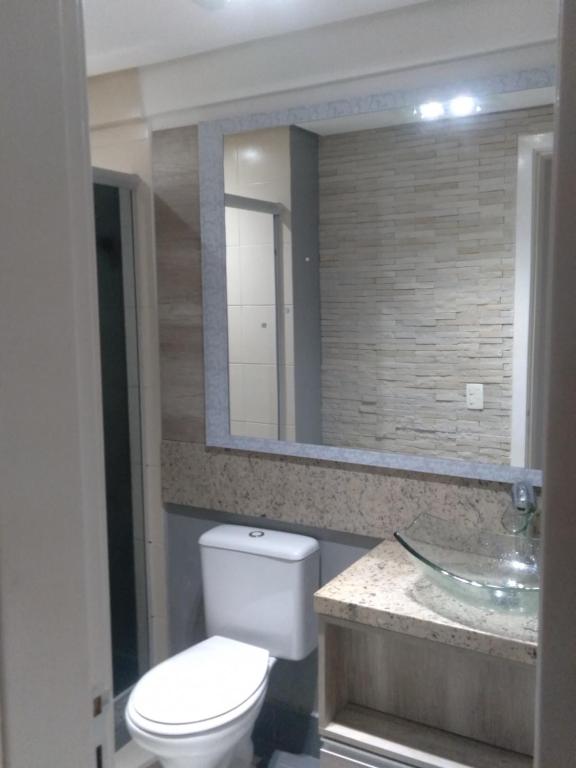 uma casa de banho com um WC, um lavatório e um espelho. em Apartamento na Serra Gaúcha em Caxias do Sul