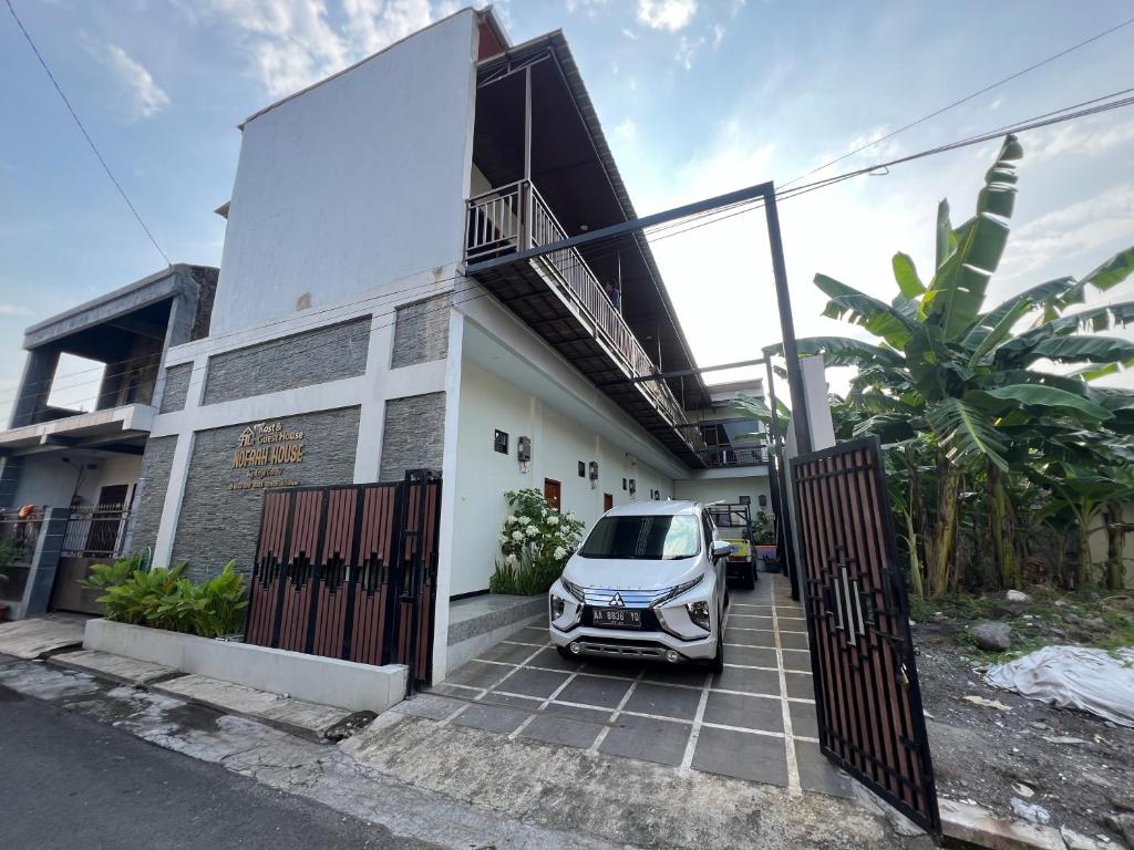 a white car parked in front of a house at Nofrah House Syariah Mitra RedDoorz in Tjolomadu