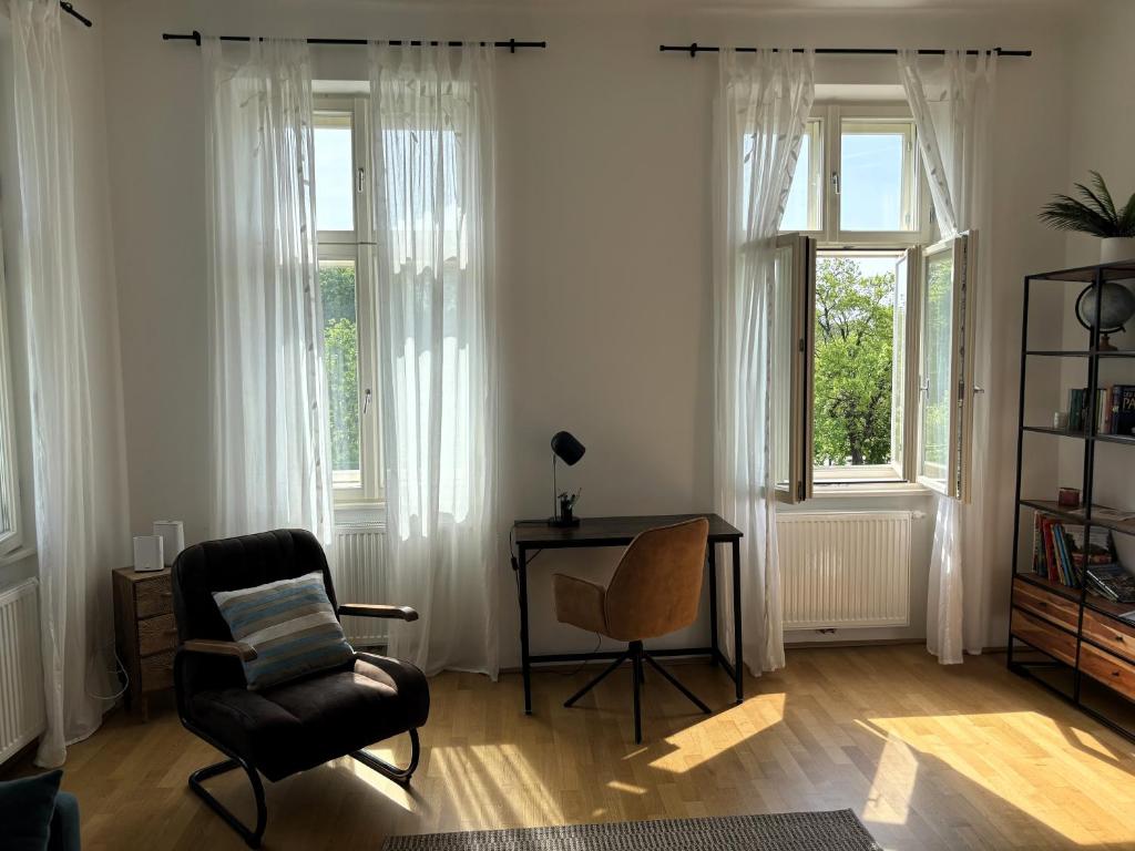 sala de estar con silla, escritorio y ventanas en Casa Nostra - Moderne lichtdurchflutete Wohnung am Augarten, en Viena