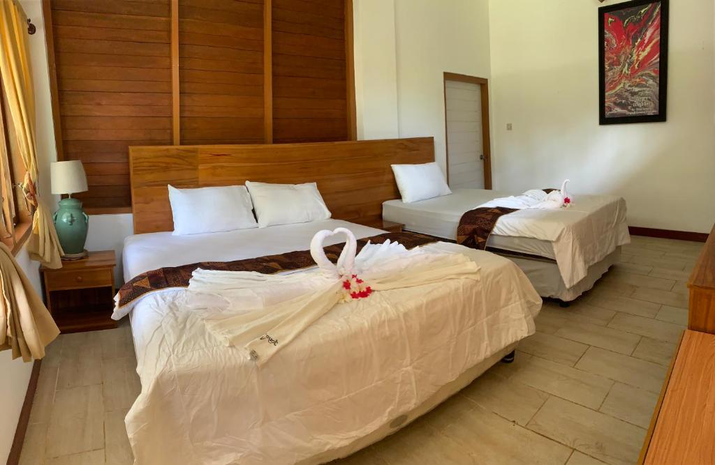 Habitación de hotel con 2 camas con sábanas blancas en Joyo’s Surf camp, en Ringinpintu
