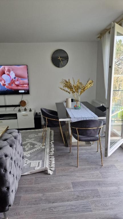 - un salon avec une table, des chaises et une télévision dans l'établissement Résidence belle air, à Porcheville