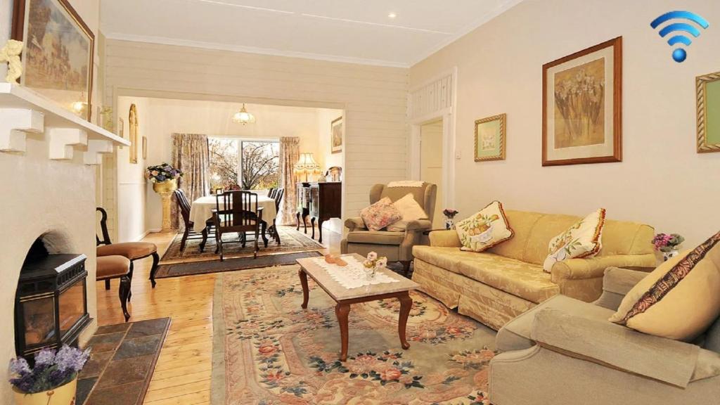 a living room with a couch and a table at Plum Tree Cottage in Bowral