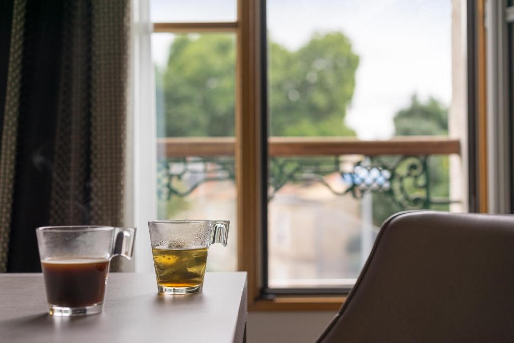 two glasses of tea sitting on a table with a window at Hôtel du Moulin in Niort