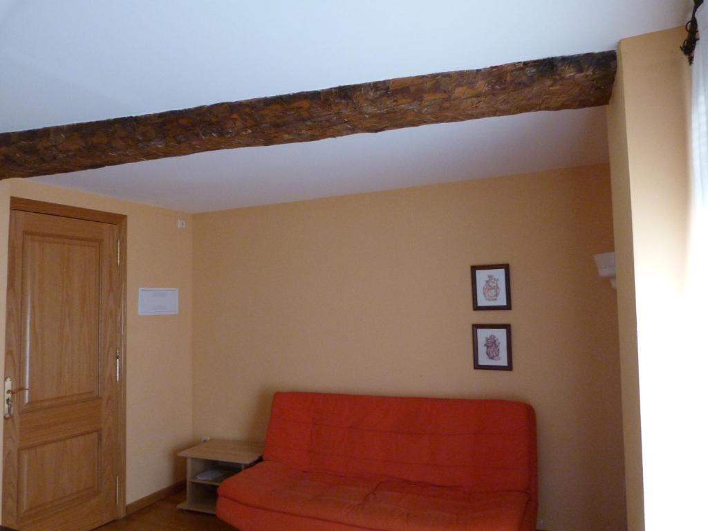 una sala de estar con un sofá naranja en una habitación en La Antigua Fonda De Villel, en Villel