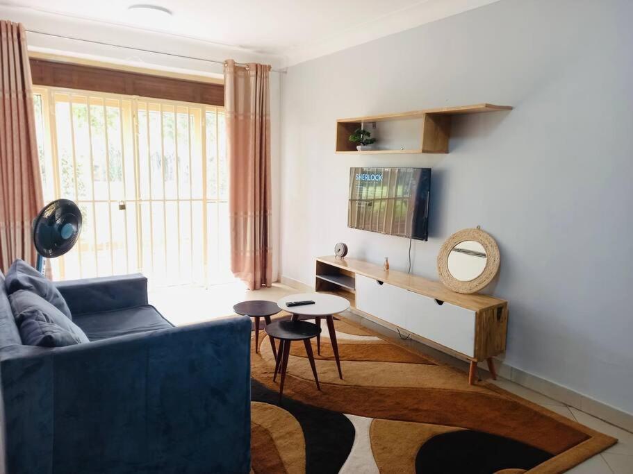 uma sala de estar com um sofá azul e uma mesa em The Lavish Condo -Wandegeya em Kampala