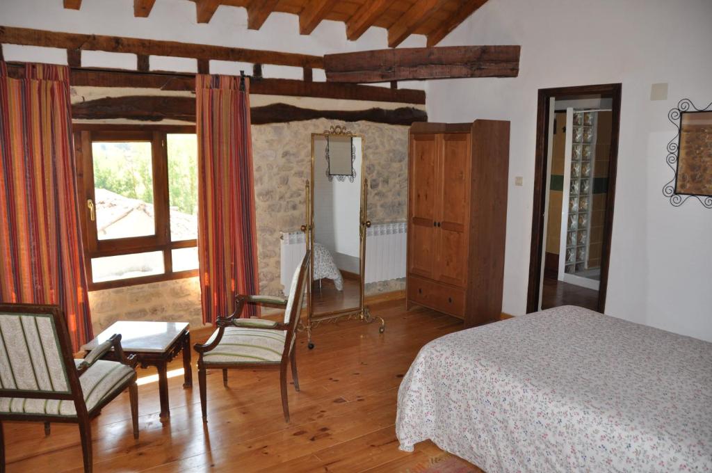 a bedroom with a bed and a table and chairs at Don Baldomero Hotel Rural in Cadiñanos