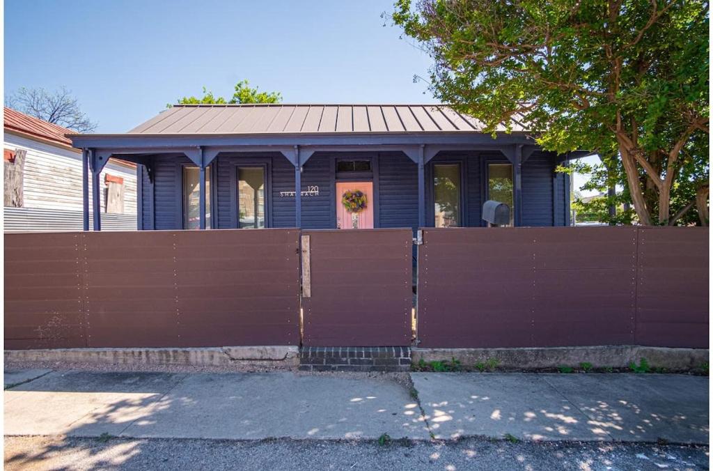 uma casa azul com uma cerca castanha à frente. em Stunning 3BR2BA Haven in Downtowns Heart em San Antonio