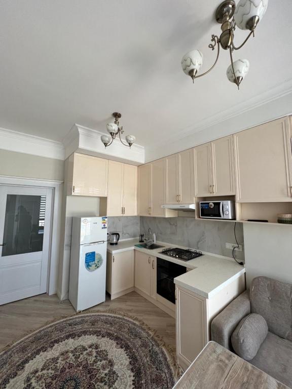 eine Küche mit weißen Schränken und einem weißen Kühlschrank in der Unterkunft Уютная квартира in Bischkek