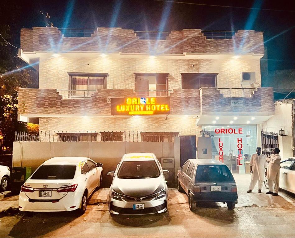 three cars parked in a parking lot in front of a building at Oriole Luxury Hotel in Islamabad
