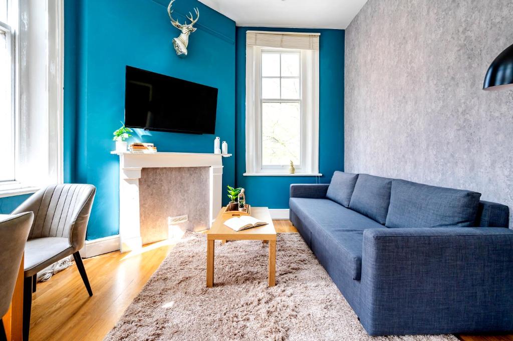 een woonkamer met blauwe muren en een blauwe bank bij Sunny Corner Apartment in Center of London (2) in Londen