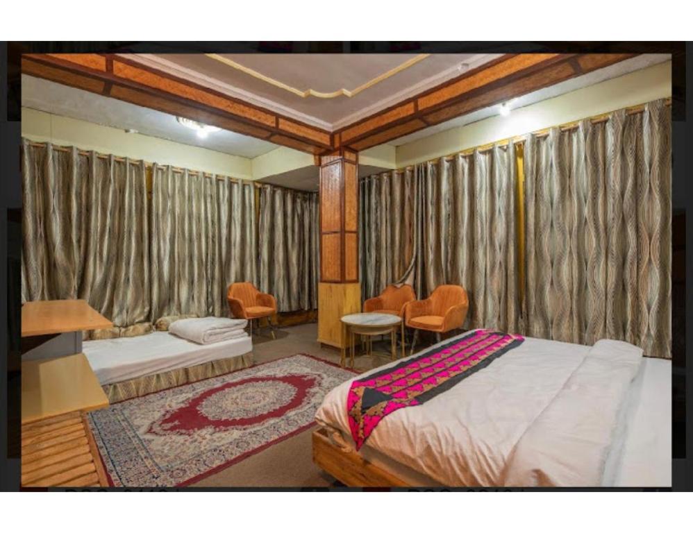 een slaapkamer met gordijnen en een bed en een bank bij Hotel Robinsson Palace, Mukteshwar in Mukteswar
