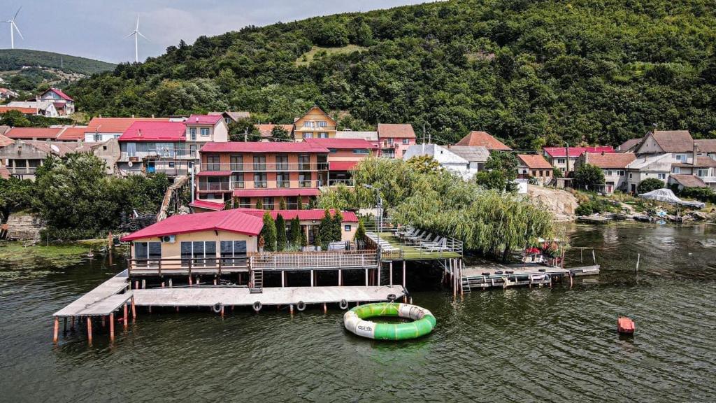 ein Haus auf einer Anlegestelle im Wasser mit einem Boot in der Unterkunft Pensiunea Leonardo in Moldova Veche