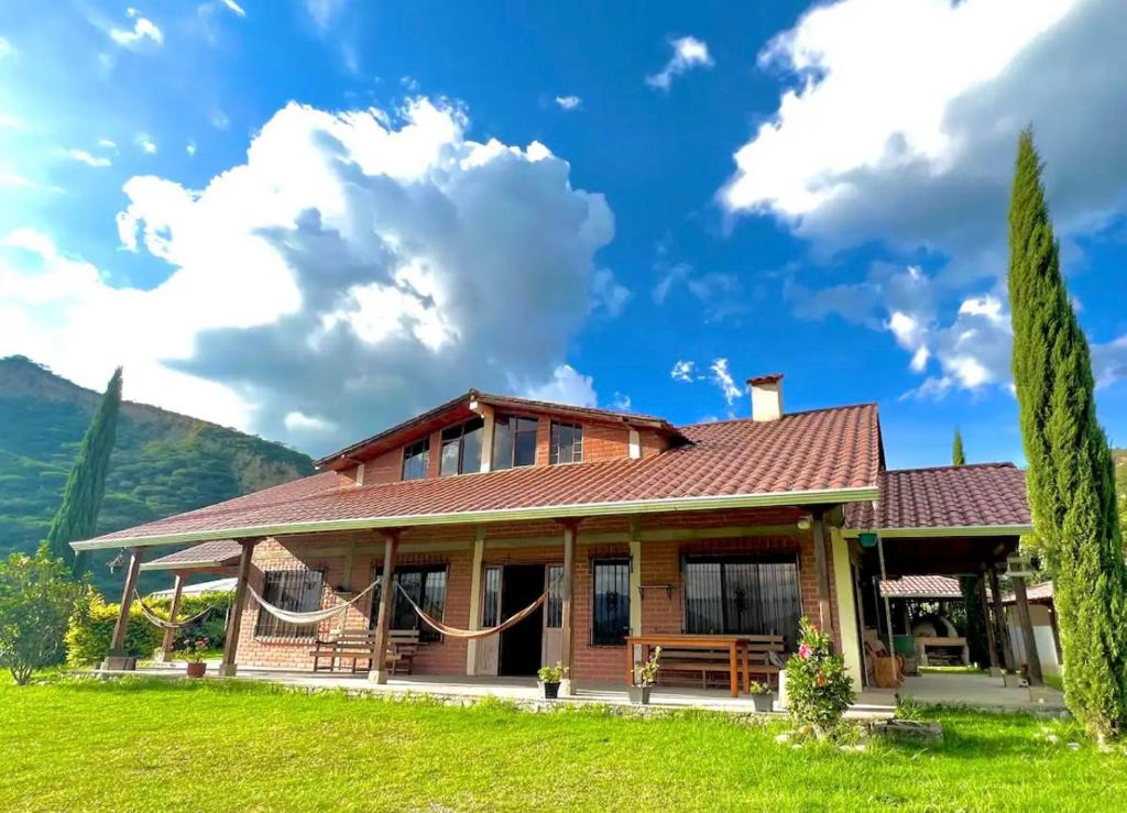 洛哈的住宿－Casa de campo acogedora con WIFI- ZONA BBQ- PARQUEO，山丘上带绿色草坪的房子