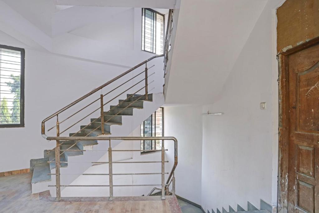 een metalen trap in een witte kamer met twee ramen bij OYO Flagship 84221 Marvel Inn in Nagpur