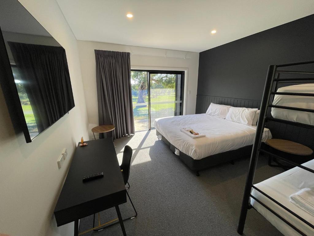 a bedroom with a bed and a desk and a bunk bed at Harden Country Club Motel in Harden