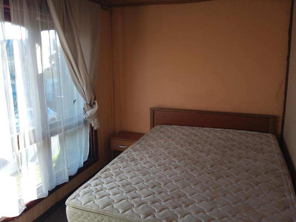 1 dormitorio con 1 cama junto a una ventana en Pensión Las Salinas, en Talcahuano