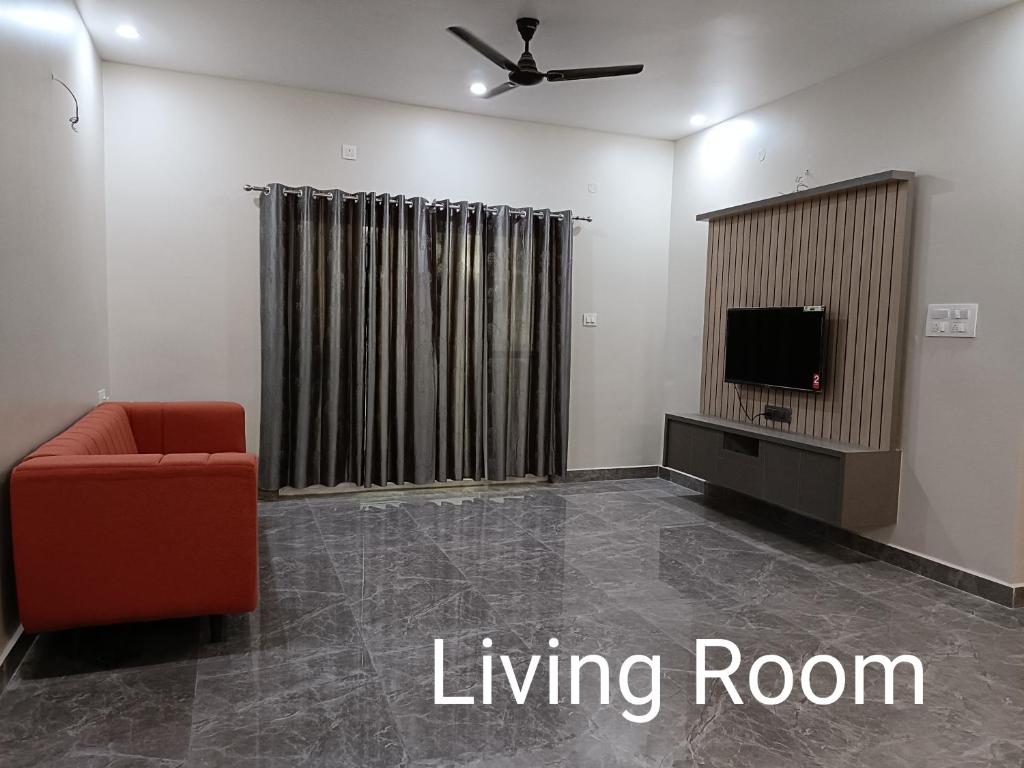 un salon avec une chaise rouge et une télévision dans l'établissement Sukrithi Premium Serviced Apartment - F2, à Chennai