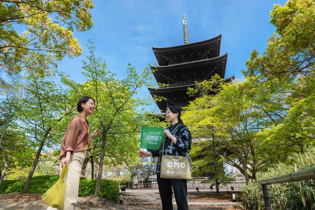 京都的住宿－OMO3 Kyoto Toji by Hoshino Resorts，站在塔前的男人和女人