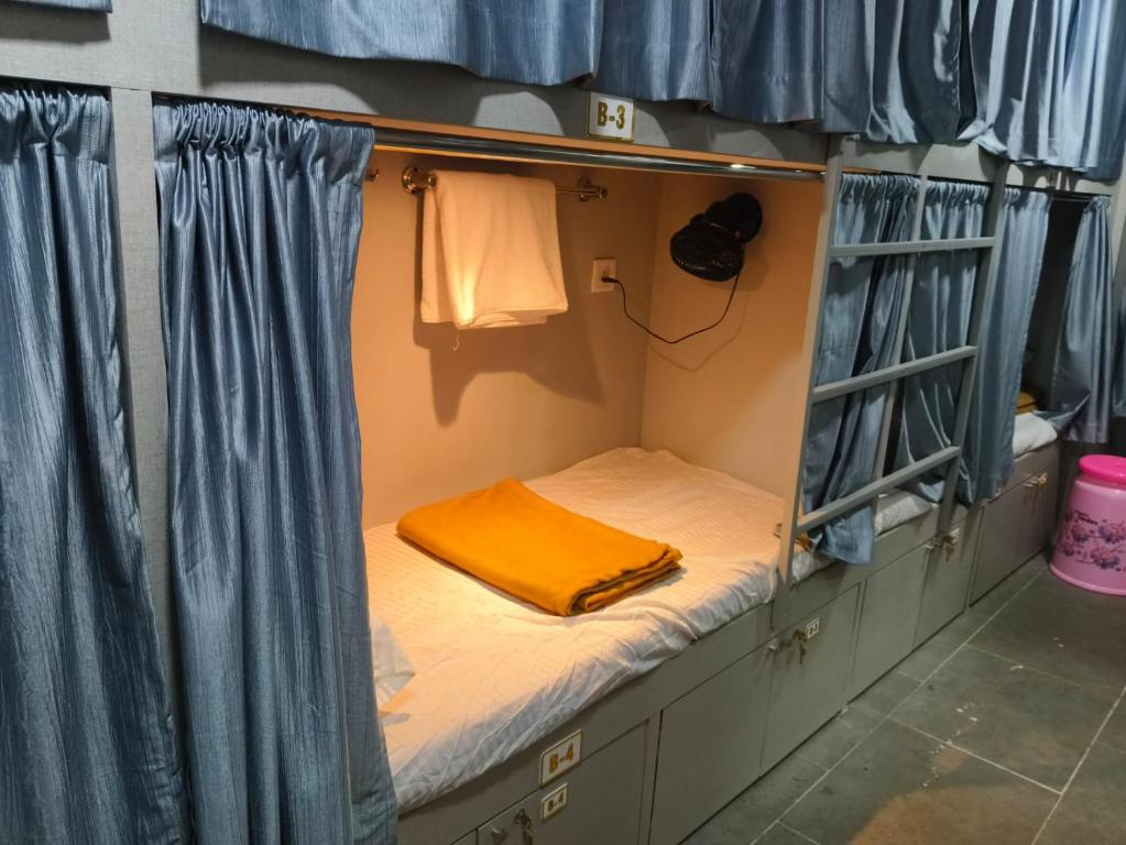 a small bed in a room with blue curtains at Rest Inn Hostel Dormitory in Mumbai