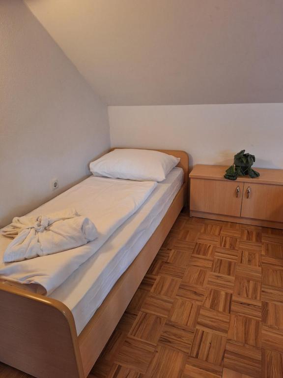 Posto letto in una piccola camera con pavimenti in legno. di Župnijski apartmaji a Dolenjske Toplice
